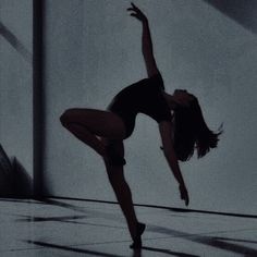 a woman is doing a dance move in the middle of an empty room with white walls