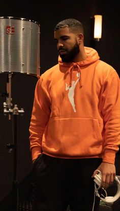 a man in an orange hoodie standing next to a lamp