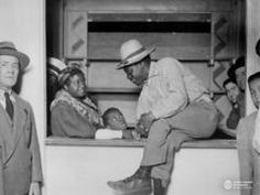 an old black and white photo of men in hats looking at something on a table