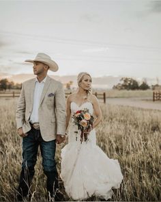 a bride and groom are walking through the tall grass