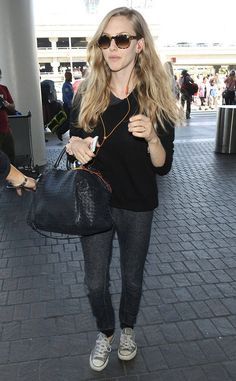 a woman carrying a black purse while walking through an airport