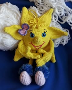 a crocheted yellow stuffed animal sitting on top of a blue blanket