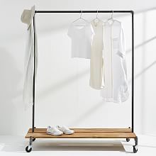 an ironing board with clothes hanging on it and two pairs of white shoes underneath