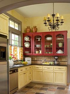 a kitchen with yellow cabinets and red cupboards in the center is seen through an archway