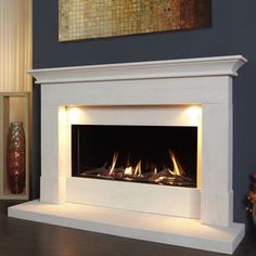 a white fireplace with two lit flames in it's center and a painting on the wall behind it