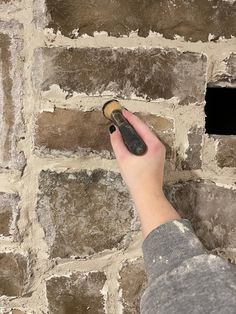 a hand pointing at a brick wall with a hole in the middle that has been built into it