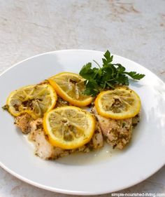 a white plate topped with chicken covered in lemon slices