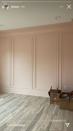 an empty room with hard wood flooring and pink paint on the walls, along with boxes