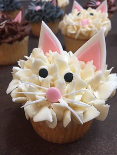 cupcakes decorated with white frosting and pink ears are sitting on a table