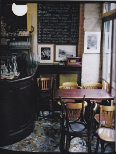 a restaurant with tables and chairs in front of a chalkboard