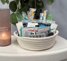 a white basket filled with items next to a candle and potted plant on top of a table