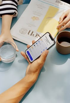 two people are sitting at a table with their cell phones in front of each other