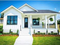 a white house with black shutters on the front door and windows in the front