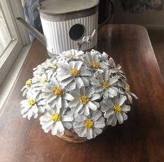 a basket filled with white flowers sitting on top of a wooden table next to a window