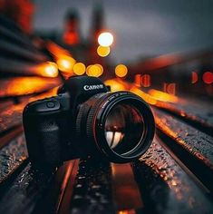 a camera sitting on top of a wooden bench next to a train track at night