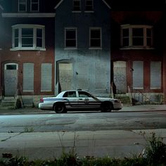 a police car is parked in front of an abandoned building on the street at night