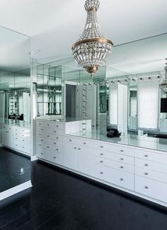 a chandelier hanging from the ceiling in a room with mirrored walls and drawers