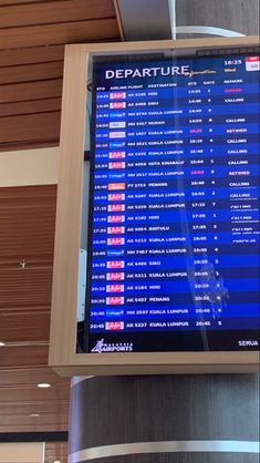 a large screen displaying the departure times at an airport