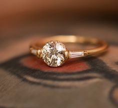 a close up of a ring with a diamond on the top and two diamonds on the bottom