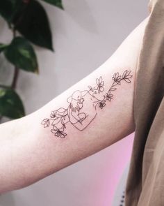 a person with a tattoo on their arm that has flowers growing out of the side