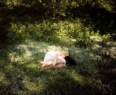 a woman laying in the grass with her head down