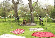 an outdoor concert set up in the middle of a field with flags and lights strung from trees