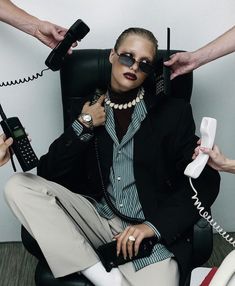 a woman sitting in a chair with two hands on her head and one holding a phone to her ear