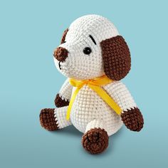 a crocheted stuffed dog with a yellow ribbon around its neck on a blue background