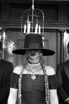 a woman wearing a hat and braids in front of two men