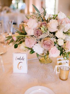 a centerpiece with flowers and greenery on a table at a wedding reception in an elegant setting