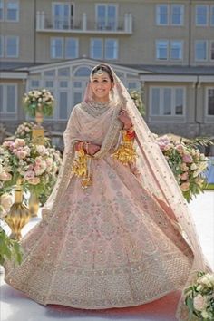 a woman in a pink and gold bridal gown is walking down the aisle with flowers