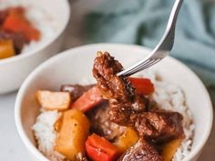 a bowl filled with meat and vegetables on top of rice next to a fork in it