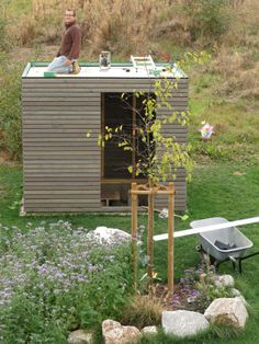 a man sitting on top of a wooden shed