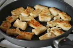 some food is cooking in a frying pan on the burner stove top and it looks like they have won't been cooked yet