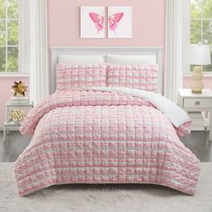 a bed with pink and white comforter in a bedroom next to two paintings on the wall