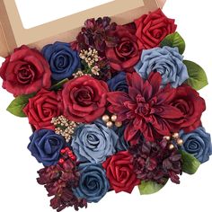 a bouquet of red, blue and purple flowers in a cardboard box on a white background