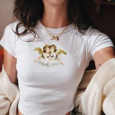 We love this fun, colorful cute Vintage Angels Baby Tee! This adult sized tee is soft and super comfy and is made of 52% cotton and 48% polyester for a luxurious lightweight stretch. The designs are printed with DTF which delivers a vivid, detailed design with a textured feel. This tee is a perfect blend of coquette fashion and nostalgic Y2K vibes, making it a trendy addition to your casual wardrobe. Made with soft, comfortable material, it's ideal for everyday wear or for making a statement at Aesthetic Summer Tops With Letter Print, White Printed Y2k Tops, Aesthetic Letter Print Summer Tops, White Cotton Aesthetic T-shirt, White Aesthetic Summer Tops, Aesthetic Graphic Print Tops For Spring, White Aesthetic Cotton T-shirt, Vintage White Top With Cartoon Print, Aesthetic Short Sleeve Tops With Letter Print