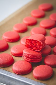 red macaroons are sitting on a baking sheet