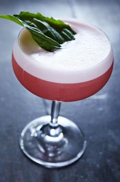 a pink and white drink with green garnish on the rim