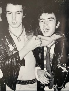 black and white photograph of two young men posing for the camera, one holding a wine glass in his other hand