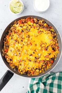 a skillet filled with mexican rice and beans next to a bowl of sour cream