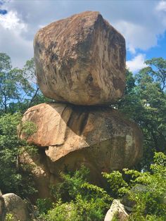 large rocks are stacked on top of each other in the middle of trees and bushes