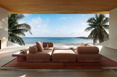 a couch sitting on top of a wooden floor next to a window filled with palm trees