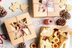 two boxes filled with cookies next to pine cones and other christmas decorations on a table