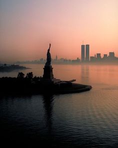 the statue of liberty is silhouetted against an orange and pink sky