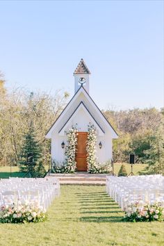 an outdoor wedding ceremony with white chairs and flowers on the aisle, in front of a church