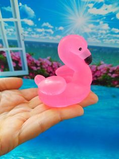 a hand holding a pink plastic toy that looks like a flamingo