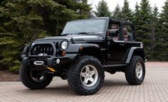 a black jeep is parked in front of some trees