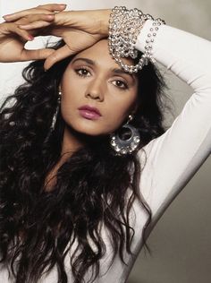 a woman with long hair and jewelry on her head, posing for a photo in front of a white wall