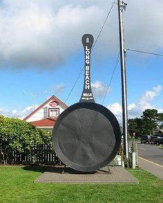 a large black object sitting on top of a lush green field next to a street